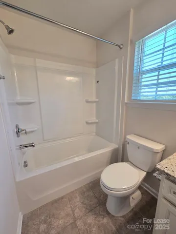 a bathroom with a granite countertop toilet sink and mirror