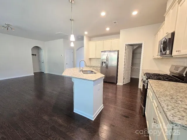 a kitchen with stainless steel appliances granite countertop a sink a stove and a refrigerator