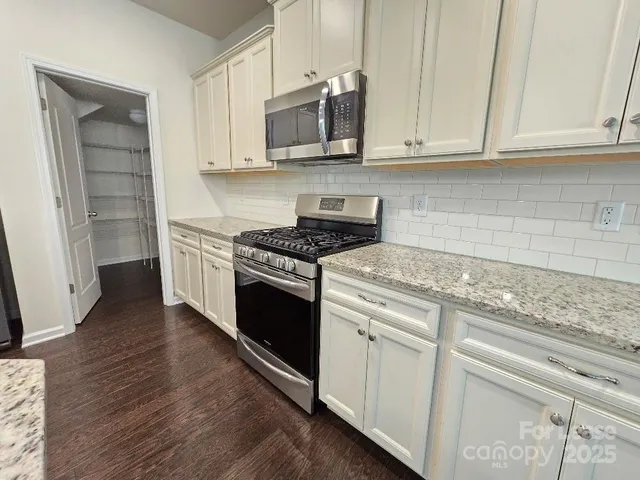 a kitchen with granite countertop a stove and a microwave