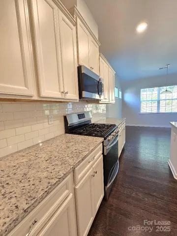 a kitchen with stainless steel appliances granite countertop a sink a stove and a microwave