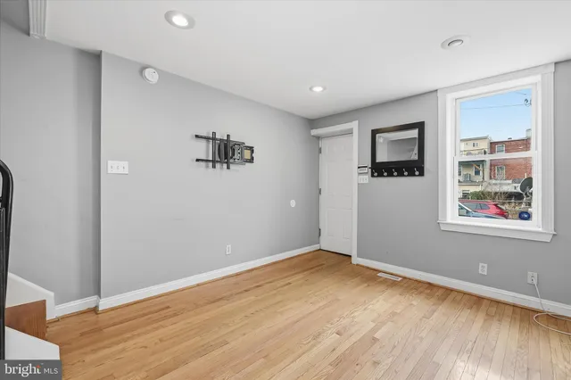 a view of an empty room with window and wooden floor