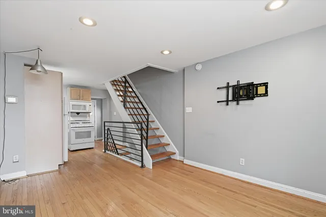 an empty room with wooden floor staircase and windows