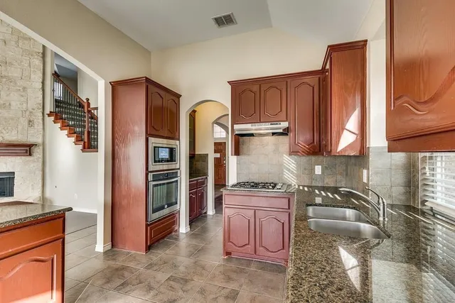 a kitchen with stainless steel appliances granite countertop a refrigerator and a stove