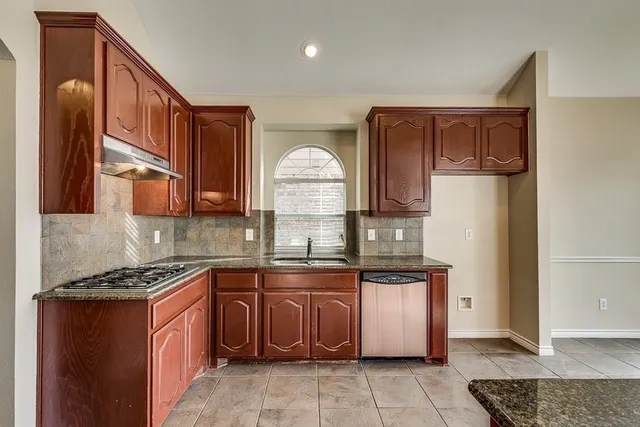 a kitchen with stainless steel appliances granite countertop a stove a sink and a refrigerator