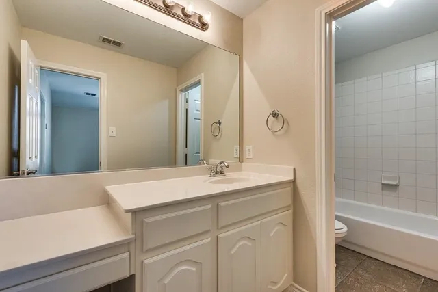 a en suite bathroom with a granite countertop sink and a mirror