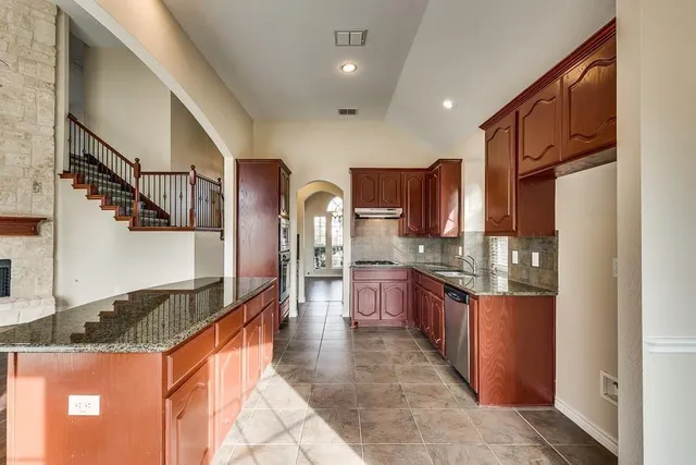 a large kitchen with stainless steel appliances granite countertop a stove and a refrigerator