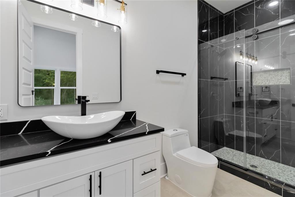 1604 Greendale Road Covington, GA 30014 - Photo 53 of 68 a bathroom with a granite countertop sink a toilet a mirror and shower