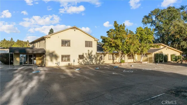an aerial view of residential house with parking and trees