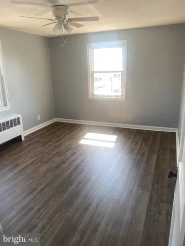 an empty room with wooden floor chandelier fan and windows