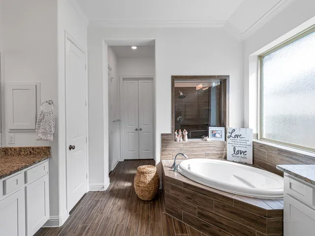 a bathroom with a granite countertop tub a sink and a large mirror