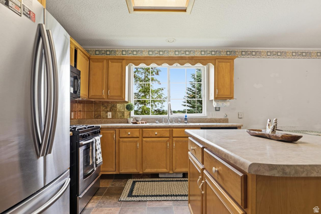 435 East 4th North Preston, ID 83263 - Photo 6 of 26 Kitchen featuring wood cabinetry, stainless steel appliances, a double basin sink, and a central island