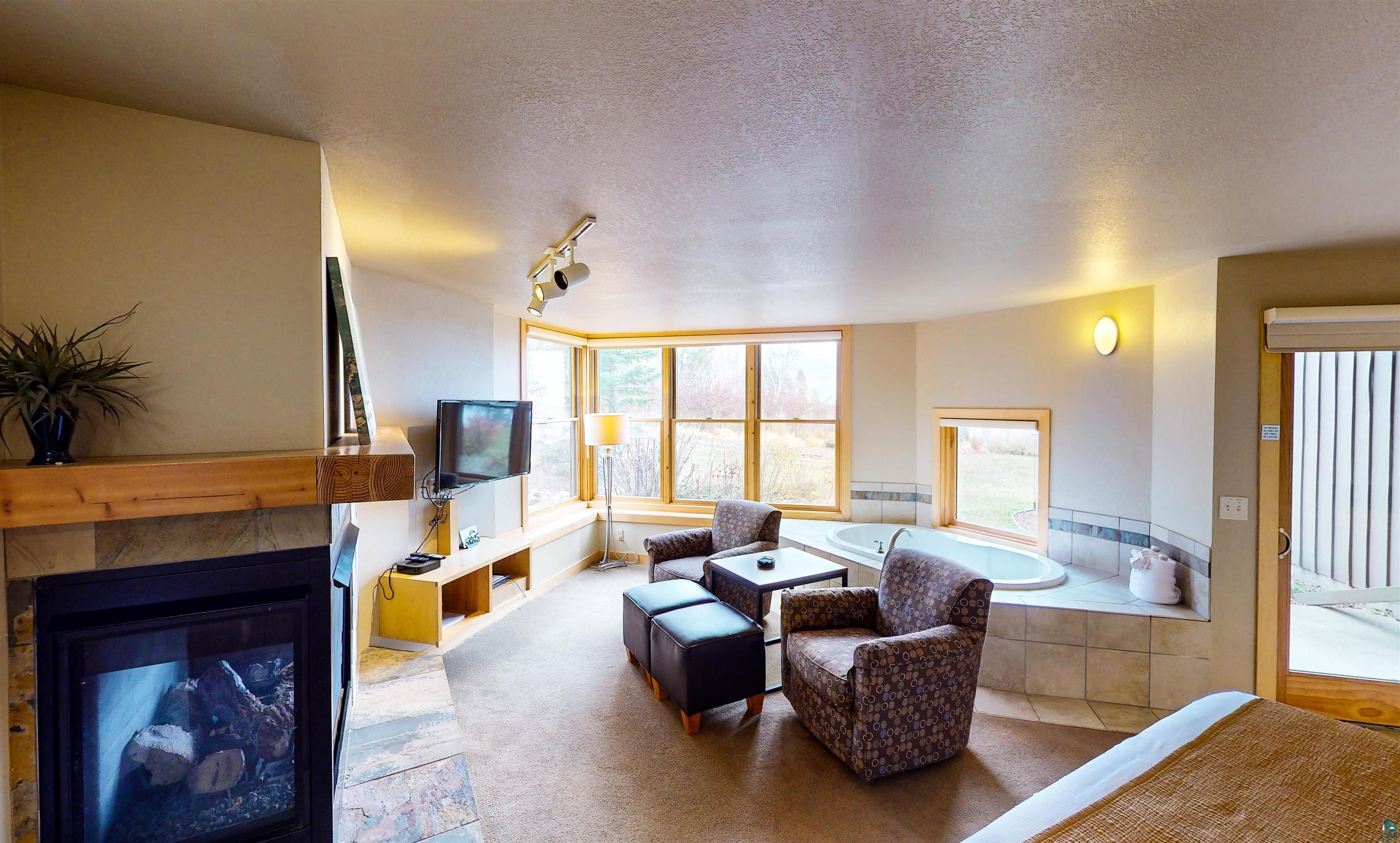40 Surfside Drive, Unit 5D Tofte, MN 55615 - Photo 19 of 37 Living space featuring a tiled fireplace with a wood mantle, a built-in entertainment console, a bay window, and a built-in jetted tub with tiled surround
