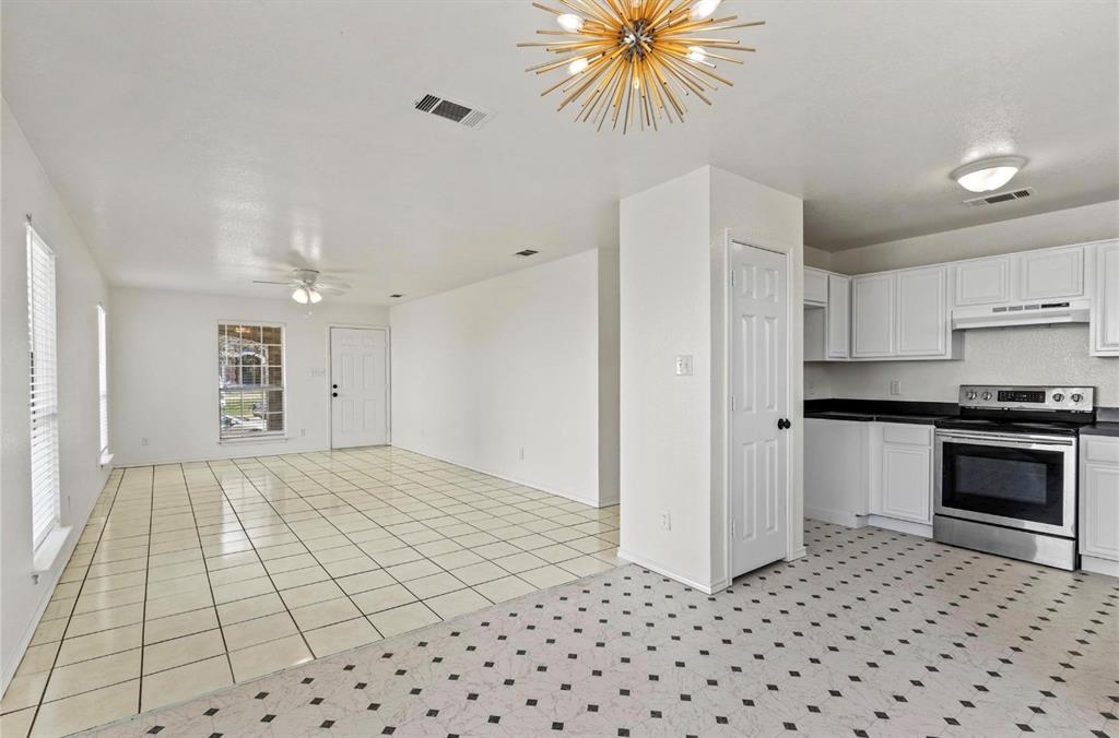 5169 East Rim Road Dallas, TX 75211 - Photo 5 of 19 Open-concept living space featuring a contemporary gold sputnik chandelier, white cabinetry, dark countertops, and stainless steel appliances
