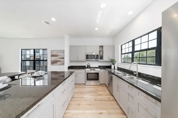 a large kitchen with granite countertop lots of counter space a sink and stainless steel appliances