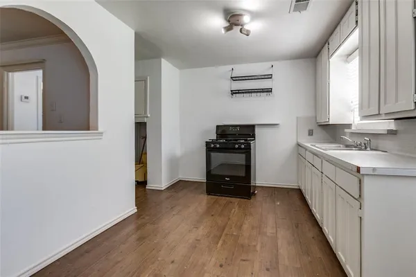 a kitchen with granite countertop a refrigerator a sink and wooden floors