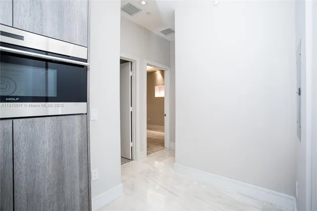 a view of a hallway with wooden floor and a bathroom