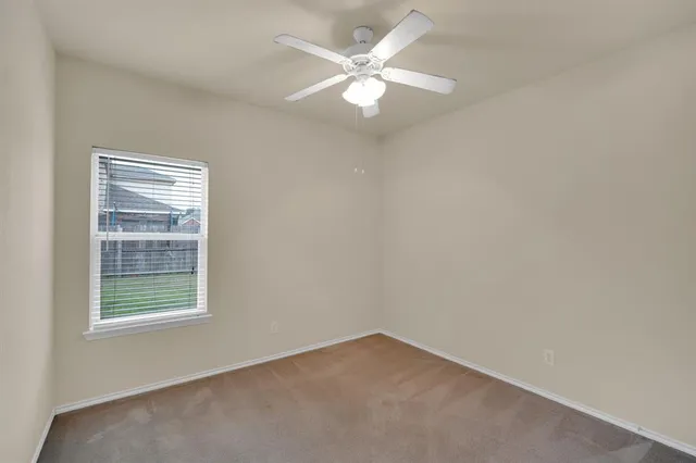 an empty room with a window and a fan