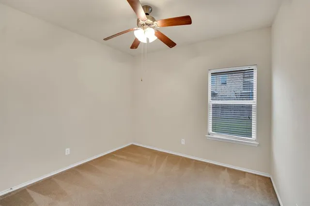 an empty room with a window and a ceiling fan