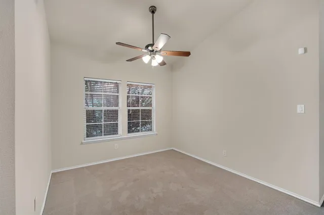 an empty room with windows and fan