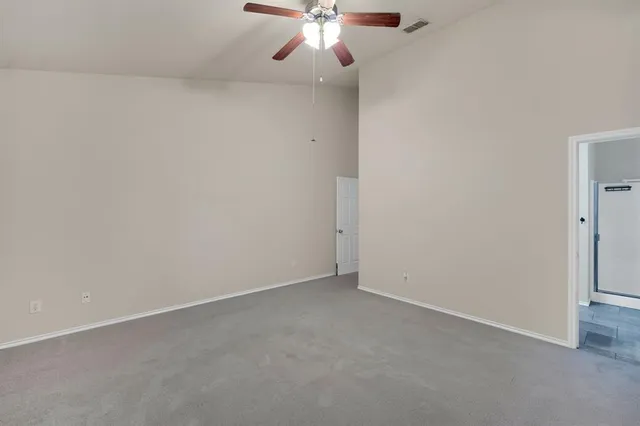 an empty room with a chandelier fan and windows