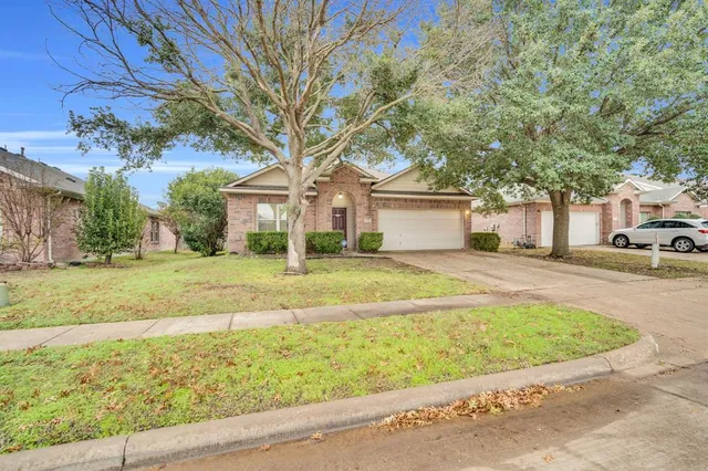 a view of a white house next to a yard with big trees