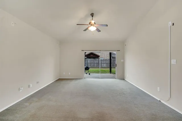 an empty room with a ceiling fan and window