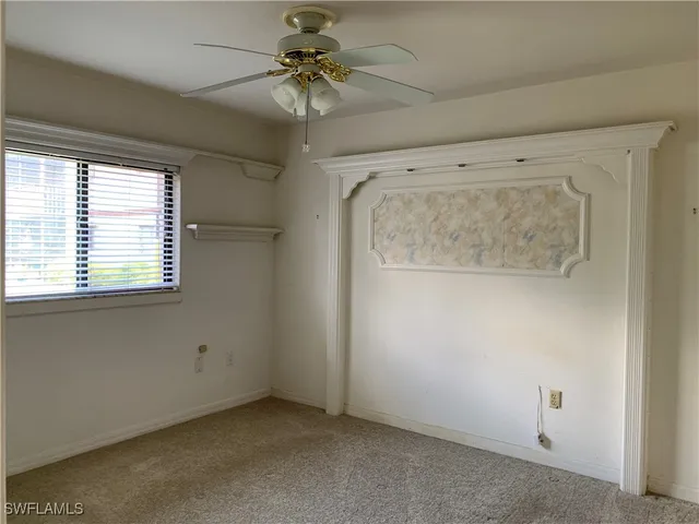 an empty room with a ceiling fan and a window