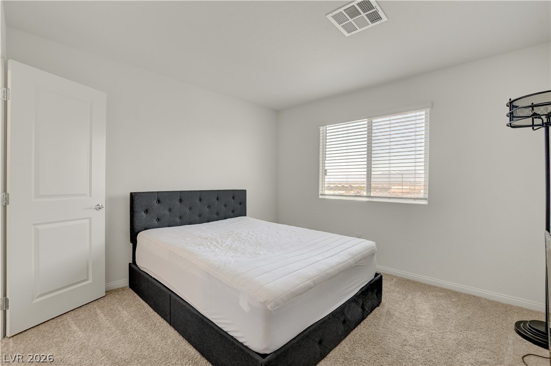 6924 Spicy Merlot Street North Las Vegas, NV 89086 - Photo 34 of 83 A well-lit bedroom offering a peaceful retreat with soft carpeting and ample natural illumination.