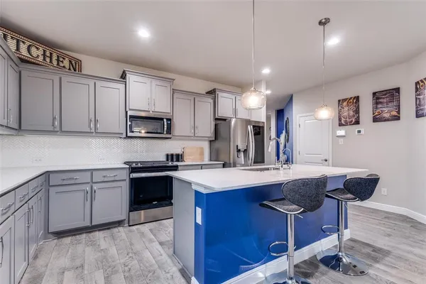 a kitchen with stainless steel appliances granite countertop a sink dishwasher a stove and a refrigerator with wooden floor