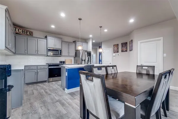 a kitchen with stainless steel appliances granite countertop a stove a sink a microwave a dining table and chairs