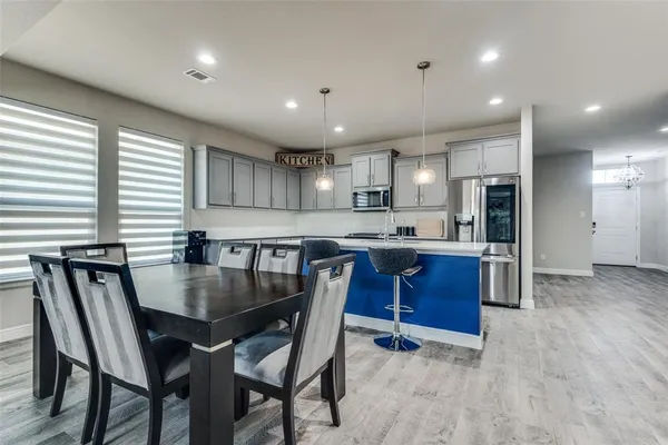 a kitchen with stainless steel appliances granite countertop a stove a sink a refrigerator dining table and chairs