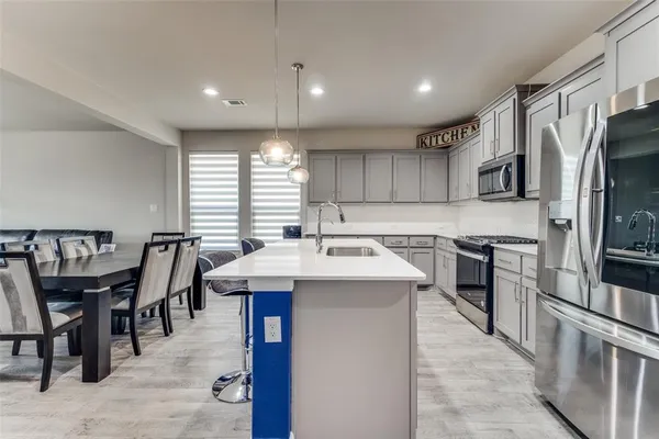 a kitchen with stainless steel appliances granite countertop a table chairs sink refrigerator and microwave