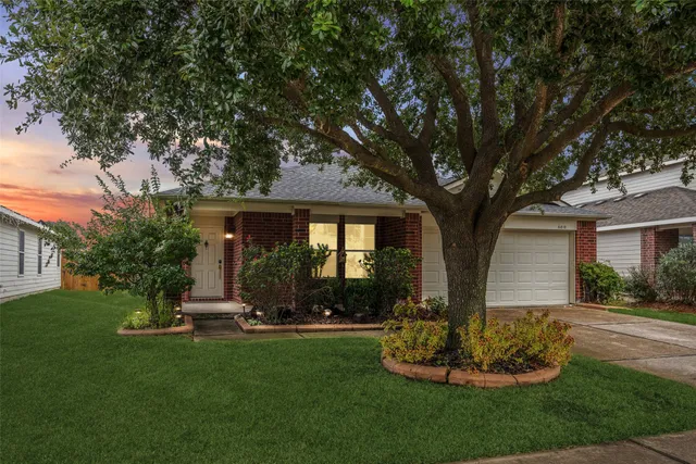 a front view of a house with a yard and tree