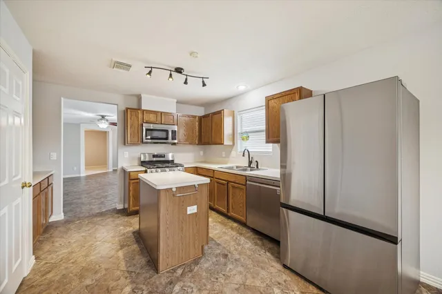 a kitchen with stainless steel appliances granite countertop a refrigerator a stove a sink dishwasher and a refrigerator with white cabinets