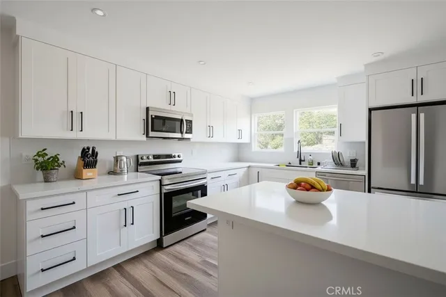 a kitchen with stainless steel appliances a stove a sink a refrigerator a window