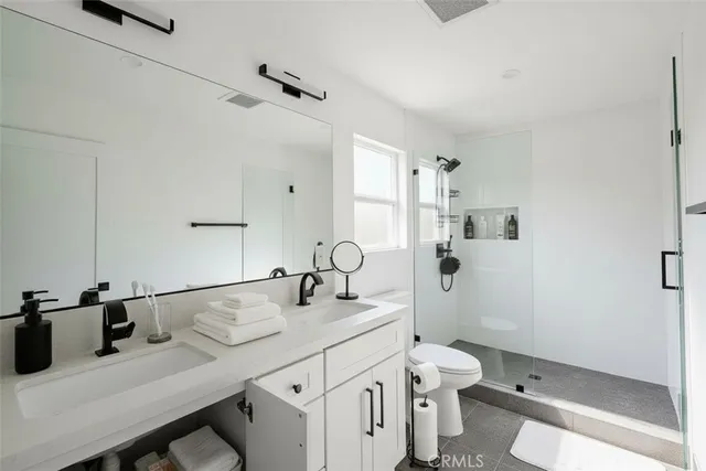 a bathroom with a granite countertop sink a toilet and shower