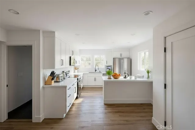 a living room with stainless steel appliances furniture and a wooden floor