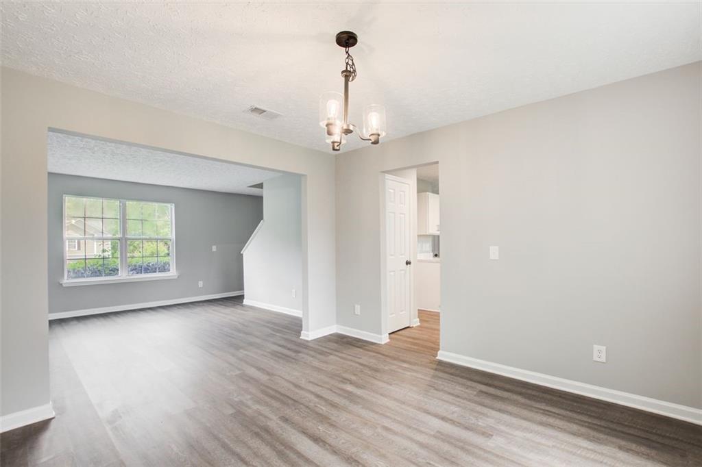 4110 Ridgebrook Bend Cumming, GA 30028 - Photo 10 of 49 an empty room with wooden floor chandelier and windows
