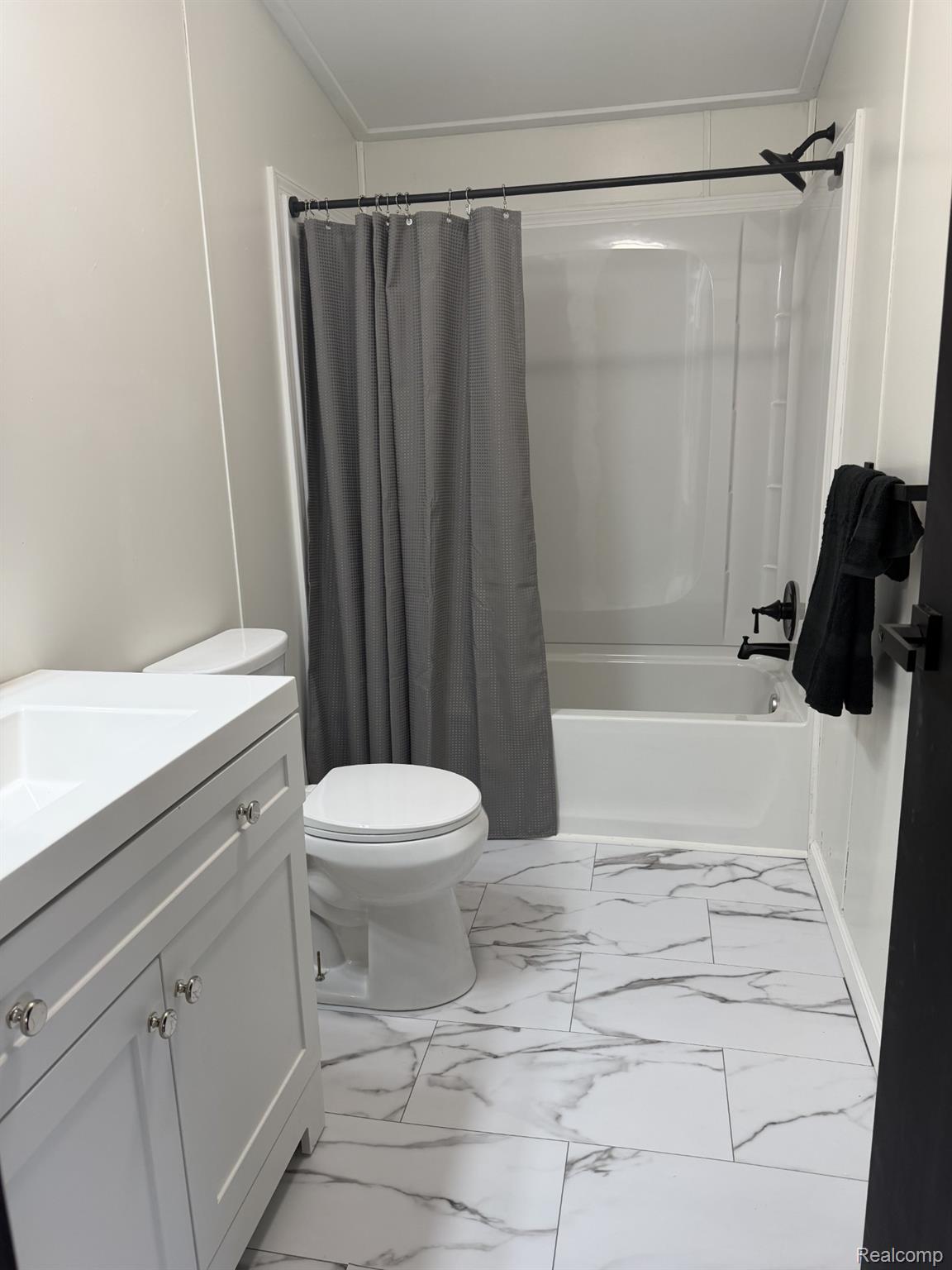 3586 Columbiaville Road Columbiaville, MI 48421 - Photo 9 of 10 Bathroom featuring a white vanity with polished chrome hardware, a white toilet, and a white tub with shower