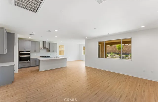 a large kitchen with stainless steel appliances kitchen island a large counter top and a wooden floors
