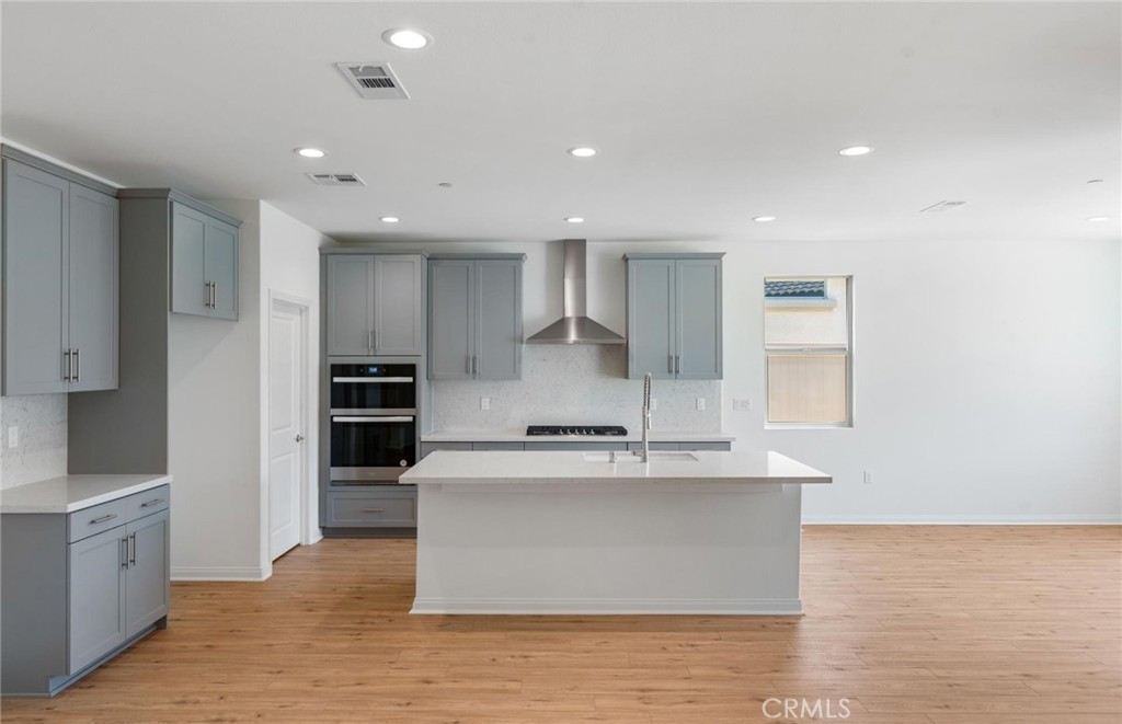 26615 Silver Ore Road Menifee, CA 92570 - Photo 3 of 30 a large kitchen with stainless steel appliances kitchen island a large counter top and a stove top oven