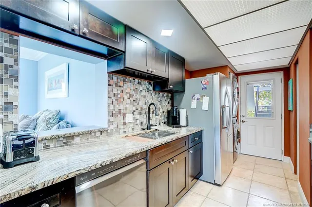 a bath room with granite countertop a sink and a refrigerator