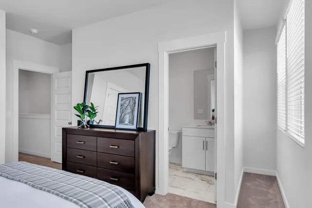 a bedroom with a bed and a potted plant on the dresser