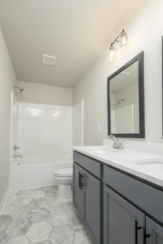 a bathroom with a granite countertop sink mirror vanity and toilet