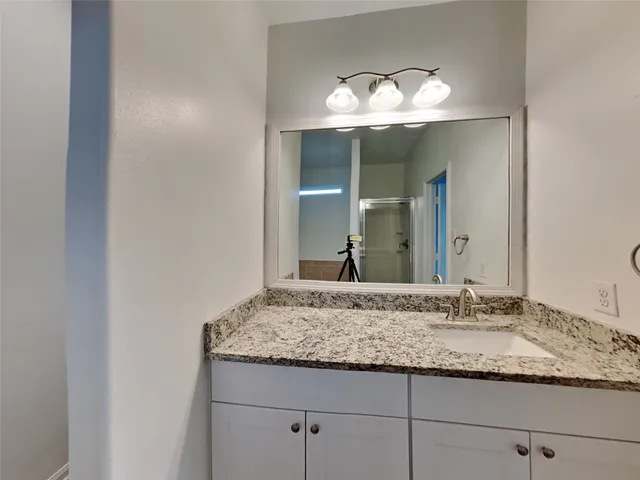 a bathroom with a granite countertop sink and a mirror