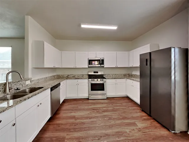 a kitchen with granite countertop white cabinets and stainless steel appliances