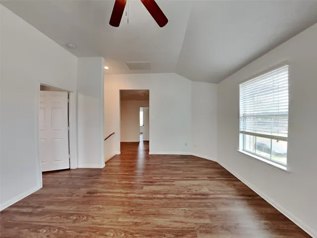 an empty room with ceiling fan and window
