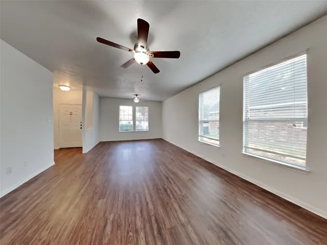 a view of an empty room with wooden floor and a window