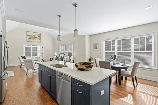 a kitchen with stainless steel appliances granite countertop a dining table chairs and a wooden floor