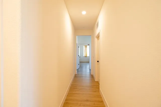 a view of a hallway with wooden floor and a living room